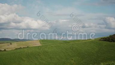 丘陵的绿色草地，有梦幻的云彩和蓝天。 托斯卡纳宁静的风景